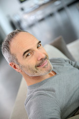 Mature smiling man sitting in couch at home