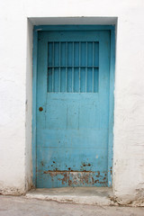 Fototapeta na wymiar Puerta vieja azul en pared blanca