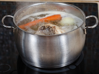 simmering chicken soup in pot on cooker close up