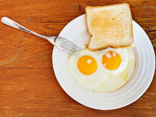 breakfast with two fried eggs in white plate