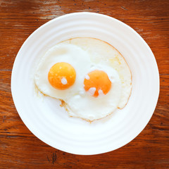 breakfast with two fried eggs in white plate