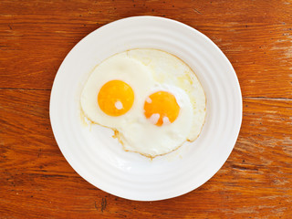 breakfast with two fried eggs in white plate