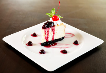 Cheesecake with berries sauce and cherry.