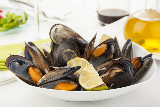 plate of coocked mussels with lemon isolated over white