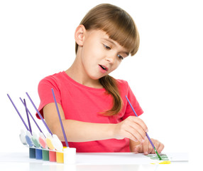 Little girl is painting with gouache