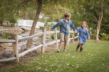 Happy Young Brother and Sister Running Outside