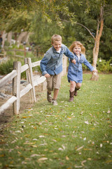 Happy Young Brother and Sister Running Outside