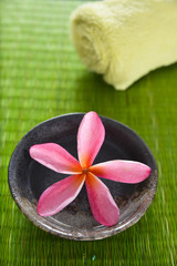 frangipani flower in wooden bowl on straw mat