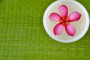 frangipani flower in wooden bowl on straw mat