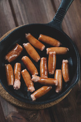 Above view of fried oily sausages in cast iron pan, studio shot