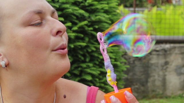 Busty woman in garden blowing bubbles