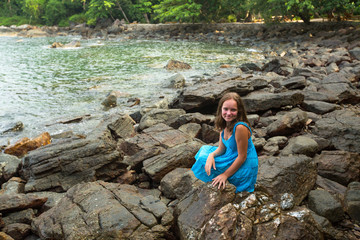Teengirl in a blue dress in the rocks of the sea coast.