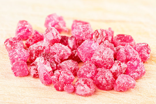 A Pile Of Raw Uncut Ruby Crystals On Wood.