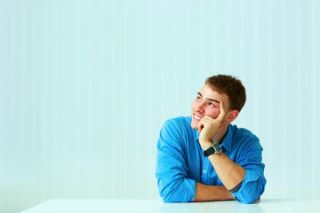 Young businessman sitting at the table and looking up in office