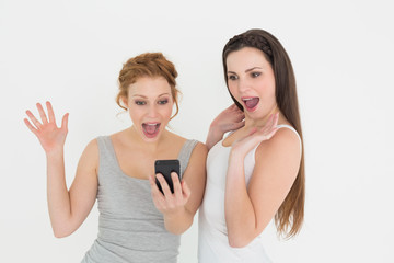 Shocked casual young female friends with mobile phone