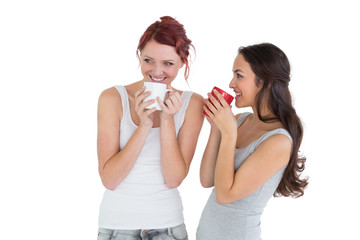 Two smiling young female friends drinking coffee