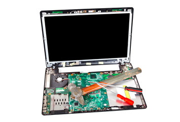 Laptop disassembled with hammer and screwdrivers on it