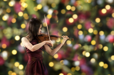 young female violin player , christmas tree