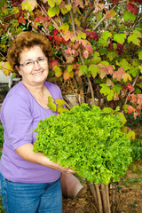 Portrait of happy housewife with raw fresh vegetable in garden