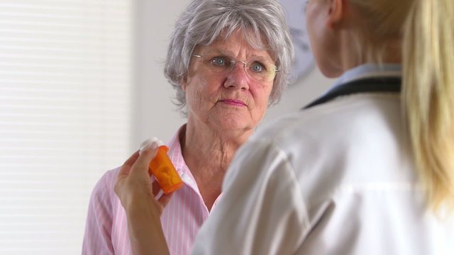 Elderly patient talking to doctor about medication pill bottle