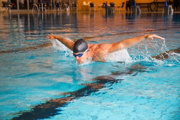 Mann schwimmt Schmetterling Stil in Schwimmbecken