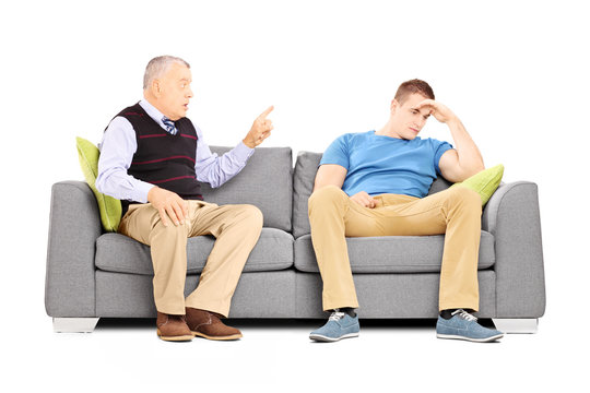 Father reprimending his son seated on a couch
