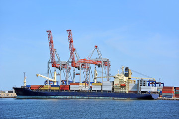 Naklejka premium Container stack and ship under crane bridge
