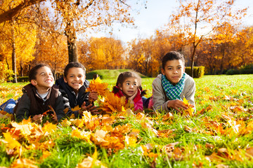 Four kids lay in autumn leaves