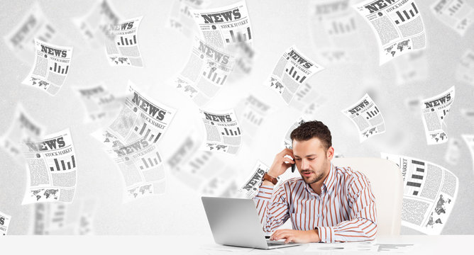 Business man at desk with stock market newspapers