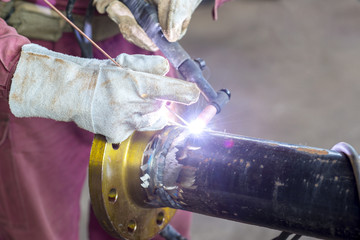 Hands welding a metal pipe