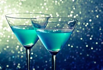 Crédence de cuisine en verre imprimé Cocktail two glasses of blue cocktail on dark green tint light bokeh