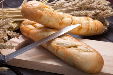 Baguettes lying on a wooden chopping board.