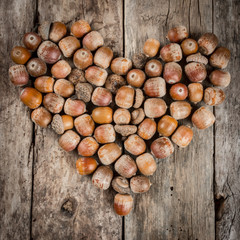 Acorns forming a heart on a wooden background