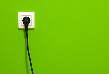 White power point with electric cable on green wall