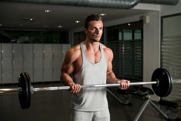 Fototapeta na wymiar Men In The Gym Exercising Biceps With Barbell