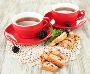 Cups of tea with cookies and blackberry on table close-up