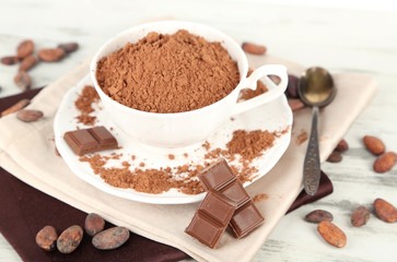 Cocoa powder in cup on napkin on wooden table