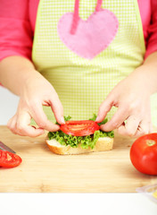 Happy smiling woman in kitchen preparing  sandwich, close up