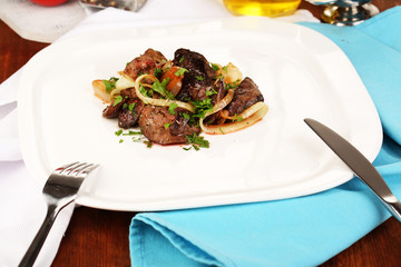 Fried chicken livers on plate on wooden table close-up