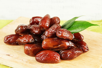Dried dates on wooden stand on table on wooden background