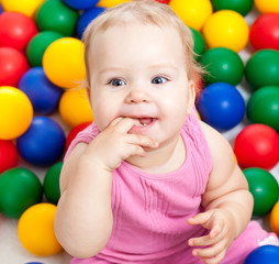 Fototapeta na wymiar Portrait of a smiling infant sitting among colorful balls