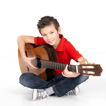 happy  boy is playing on acoustic guitar