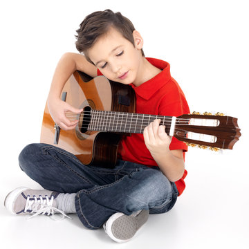 Smiling boy is playing the acoustic guitar