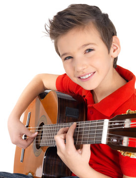 Smiling boy is playing on acoustic guitar