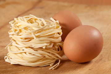 Nests of dry pasta on wooden table.