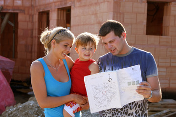Familie vor Rohbau baut ein Haus