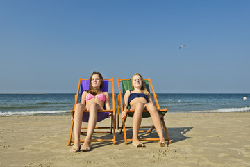 Mädchen auf zwei Liegen am Strand