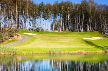 Golf course in autumn, grass field and lake