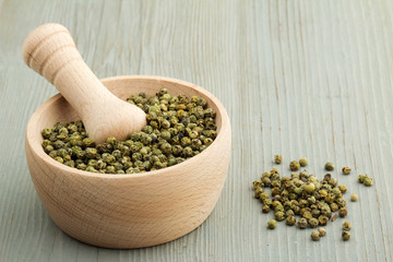 green peppercorns on wooden table