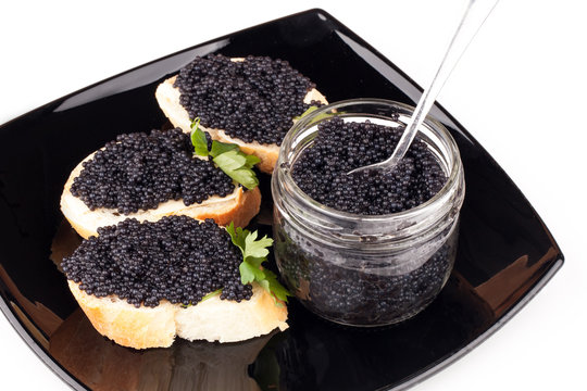 Small sandwiches with black caviar on dark plate